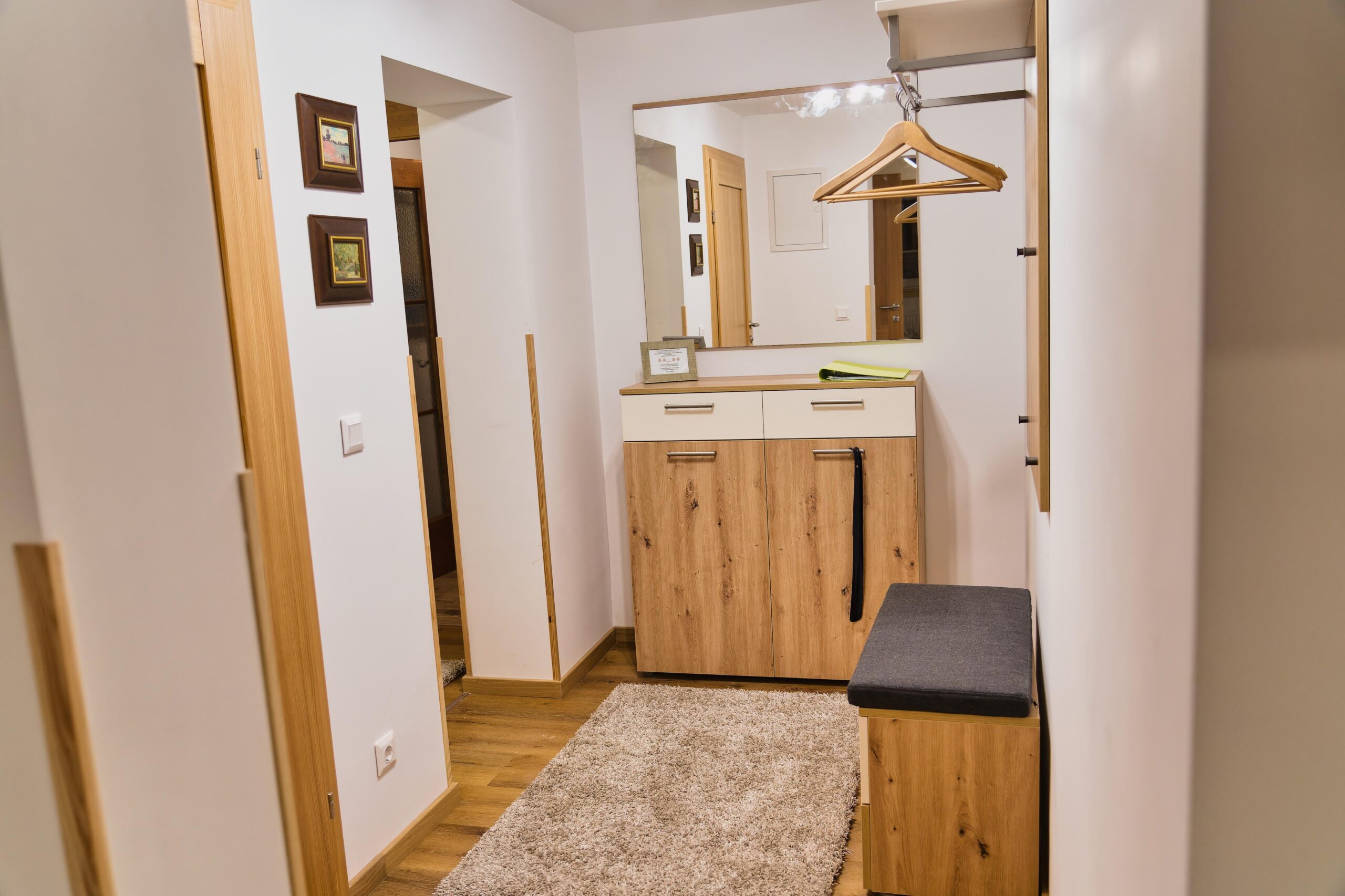 Flur der Ferienwohnung Moschelitzenblick mit Garderobe, Spiegel und kleiner Sitzbank.