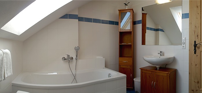 Helles Badezimmer mit Badewanne, Waschbecken und Handtuchtrockner.