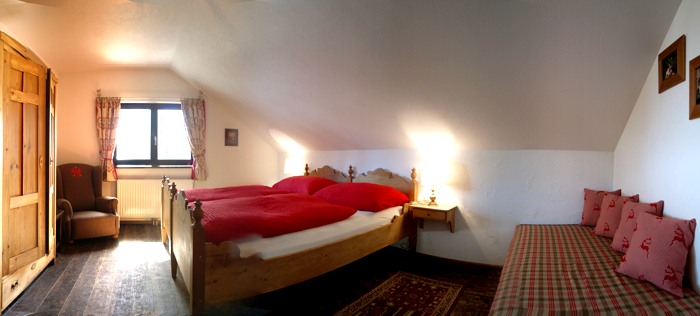 Geräumiges Schlafzimmer mit Doppelbett aus Altholz und zusätzlichem Einzelbett.