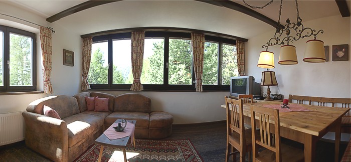 Großzügiger Wohnraum mit gemütlicher Wohnlandschaft, Massagesessel und Panoramafenster mit Bergblick.