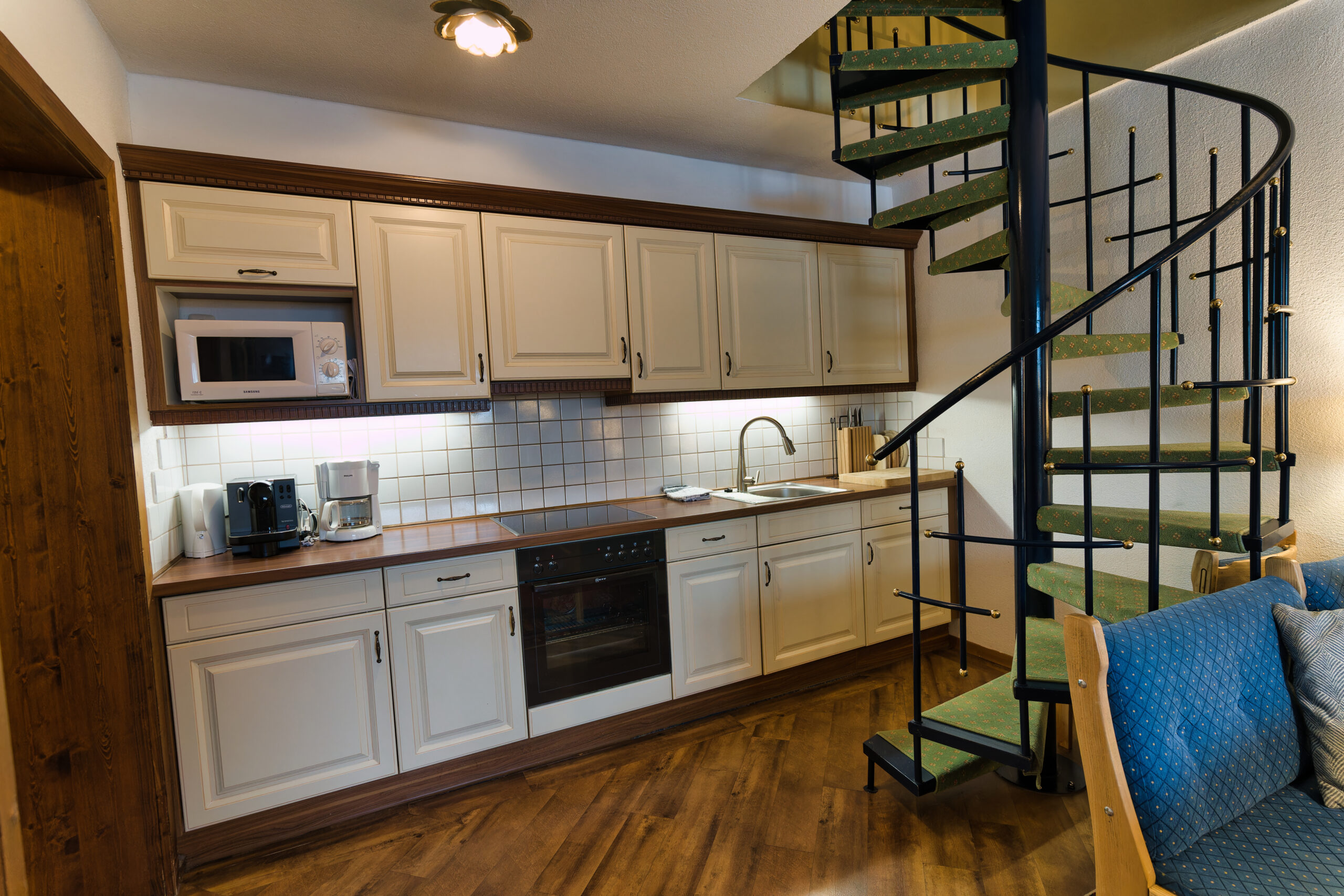 Offene, voll ausgestattete Küchenzeile mit Geschirrspüler, Herd, Kühlschrank und Kaffeemaschine.