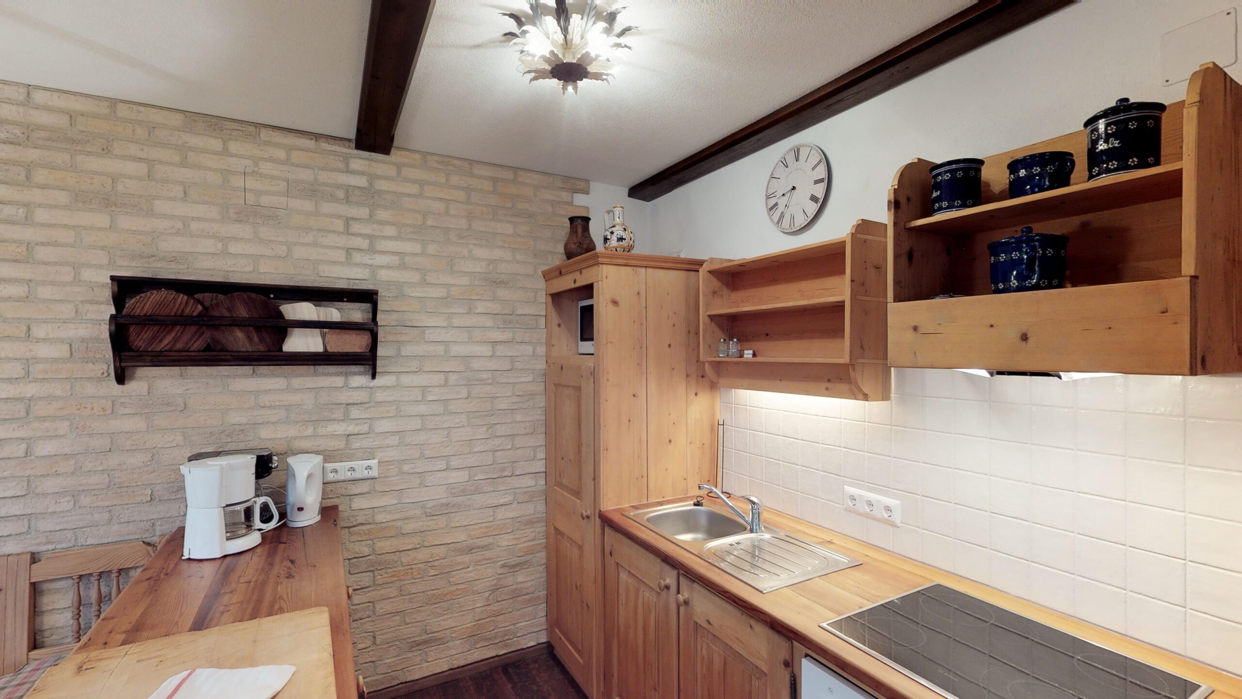 Offene Küche aus Altholz mit Geschirrspüler, Herd, Kühlschrank und Kaffeemaschinen.