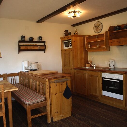 Essbereich mit altem Bauerntisch, Eckbank und Stühlen im gemütlichen Wohnraum.